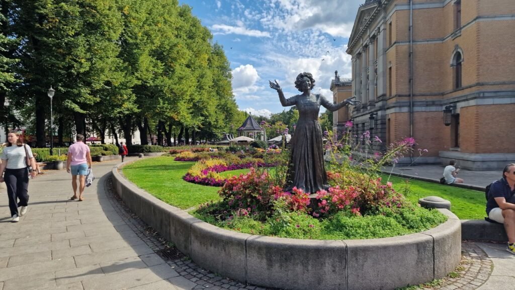 The statue of Wenke Foss at Studenterlunden Park, Nationaltheatret in the background